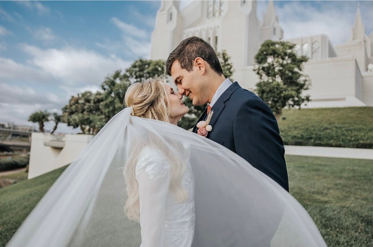 Bride and groom about to kiss beneath her flowing veil