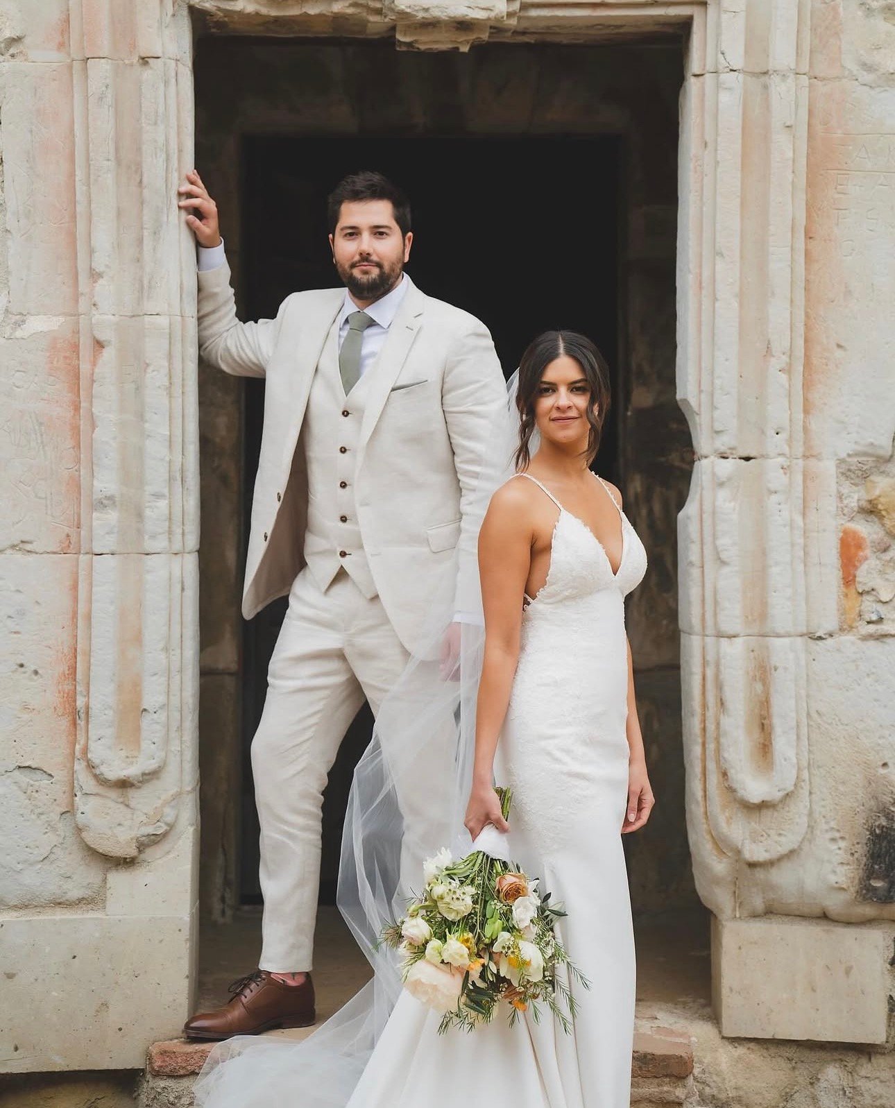 Bride and groom posing in a historic stone doorway