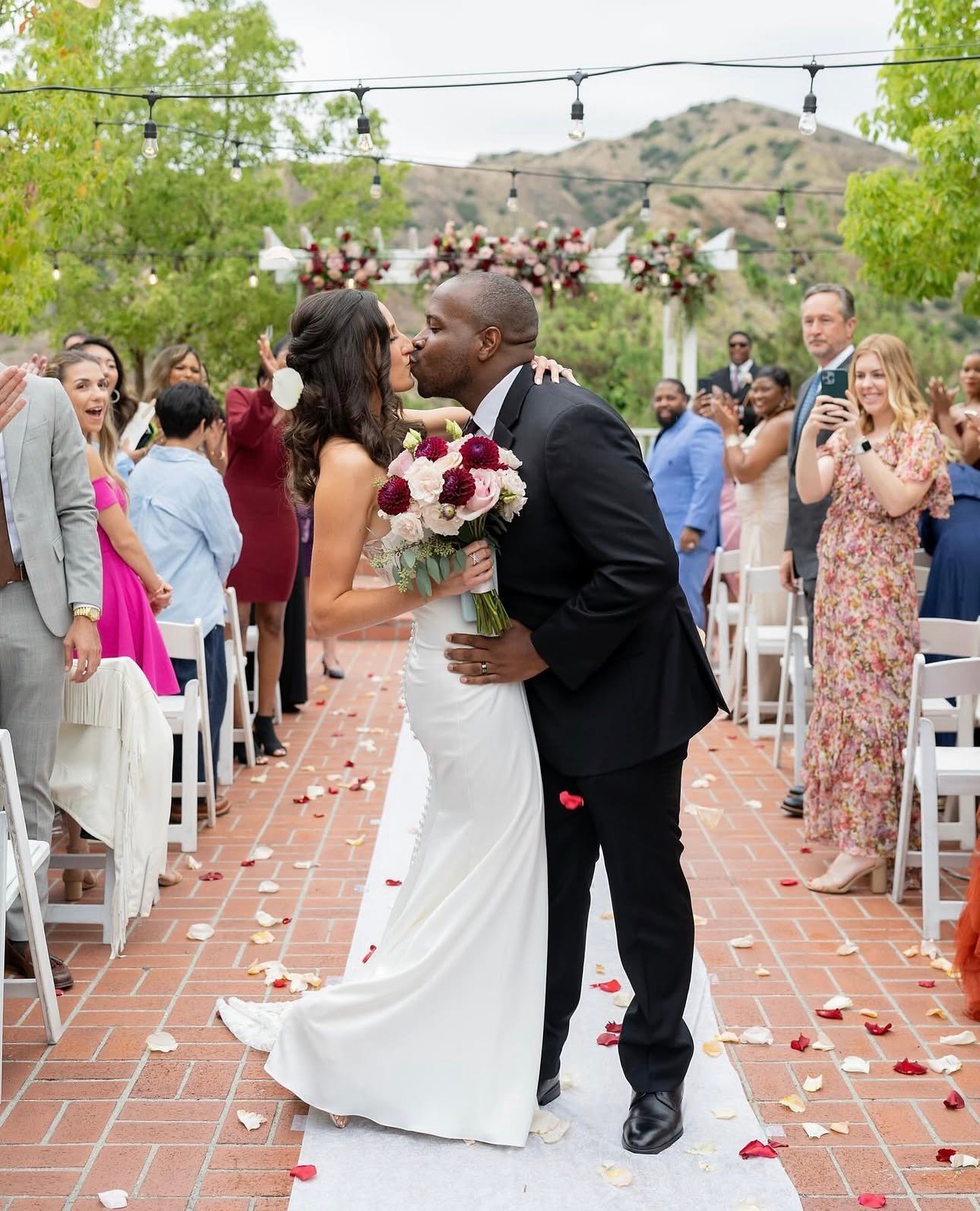 Bride and groom kissing in the aisle as guests cheer